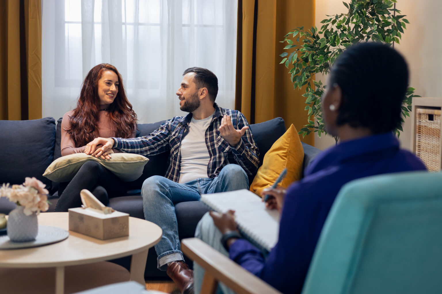 A couple sitting together on a couch, talking with a counselor